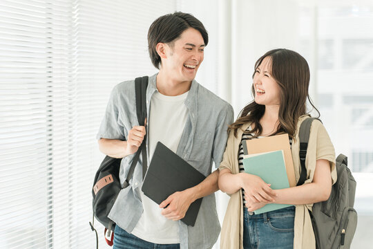 大学・短大・専門学校の校舎・キャンパスを歩く男女カップル・同級生の学生
