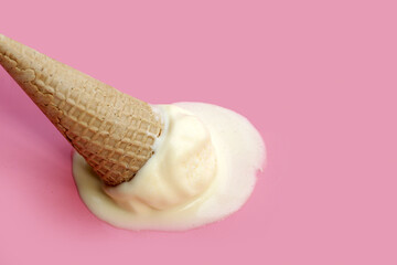Melting ice cream ball with waffle cone on pink background.