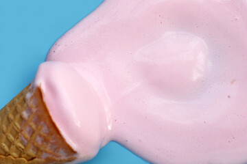 Melting ice cream ball with waffle cone on blue background.