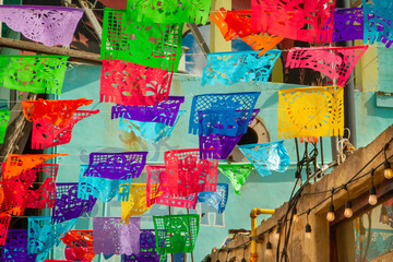 Colorful festive flags hanging against a colorful building background in Rosarito Mexico