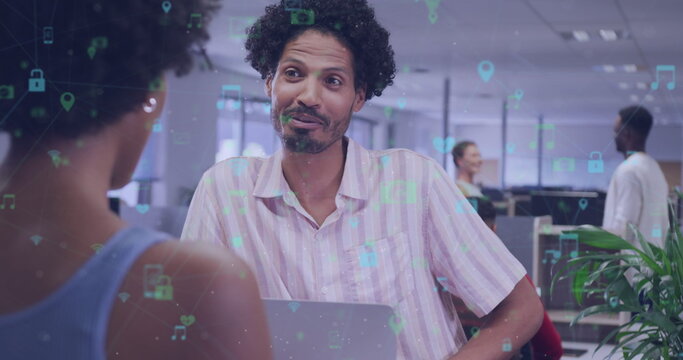 Image of connected icons over diverse coworkers having conversation in office