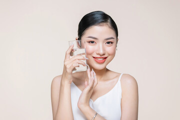 Young adult woman holds a glass of water in her hand near face