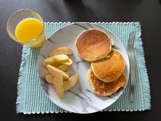 Desayuno de panecillos con jugo de naranja y manzana rebanada. 