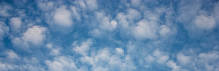 Floating clouds in the sky on a clear day. White clouds on the blue sky in summer. Lots of fluffy...