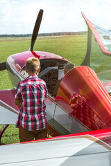 A Young Boy Watching And Learning How To Fly A Red Aerobatic Plane