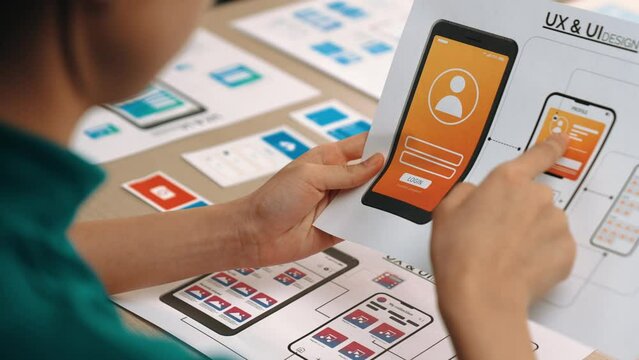Excellent startup company employee planning for user interface prototype for mobile application or website in office with model on desk. UX UI designer consider user friendly interface plan. Synergic