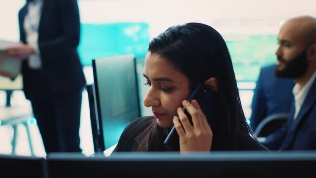 Indian financial consultant answering a phone call from a stakeholder, ensuring progress by communicating key performance indicators. Confident employee shares the current situation. Camera A.