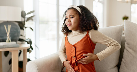 Young girl, stomach ache or allergies on couch in home for health problem or digestion recovery on...