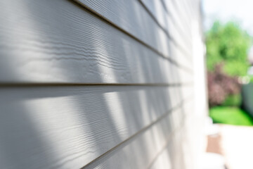 Close-up of a wooden house siding showing texture and details, with shadows and sunlight creating a natural pattern