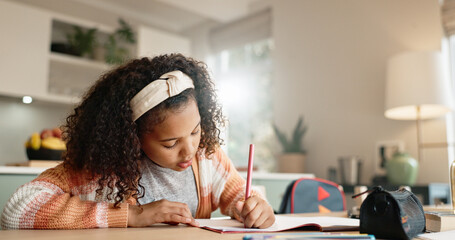 Little girl, student and writing with book in kitchen for homework or assessment at home. Young...