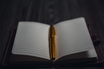 A notebook with a gold pen on the table in the candlelight