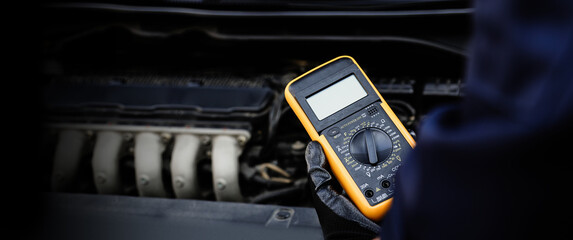 Car mechanic use voltmeter to check voltage battery low energy problem for car care service maintenance and re charger or jump start or change battery replacement.
