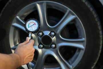Hand car mechanic holding car tire pressure check equipment tool to checking low tire pressure inflating tires to or refill or air inflate to safety and car care service maintenance inspection. © Eakrin