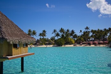 Overwater bungalows of the Intercontinental Le Moana sit over crystal clear, warm, pastel-colored waters of Bora Bora