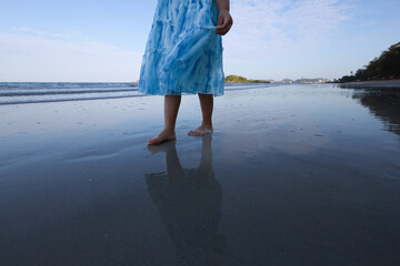 A little girl walks barefoot along the beach in the morning, leaving footprints on the sand and...