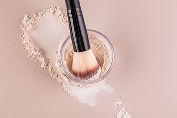 Glass jar with loose powder, swatch powder and makeup brush, applying powder on face on beige...