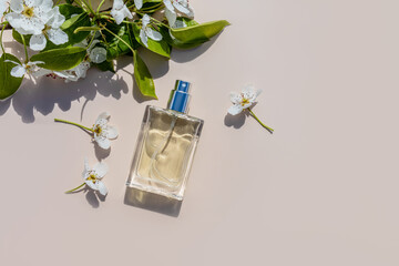 An elegant bottle of cosmetic spray or perfume on a light background among the tree branches....