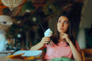 Woman Counting Calories Holding a frappe with Cream. Girl overthinking what she eats and drink...
