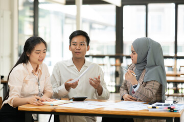 Asian business group discussing graph work at the office