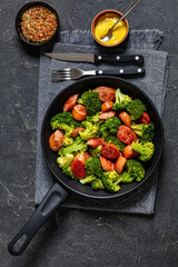 fried juicy sausage and crispy broccoli in skillet