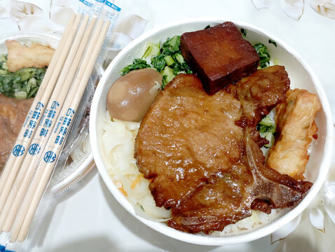 Kaohsiung, Taiwan - May 25, 2024: Taiwan Railway lunch box.  Round bento carton lunch.  Rice, pork ribs, dried tofu, eggs and vegetables.  Traditional train lunch.  Nostalgic lunch box.