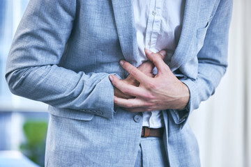 Businessman, office and hands on stomach with pain from diarrhea, food poisoning or ibs in workplace. Indigestion, constipation and bloated from overeating or appendicitis with hernia or poor diet.