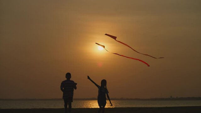 Front view of children running and flying kites at sunset by the lake, a peaceful moment of joy and freedom