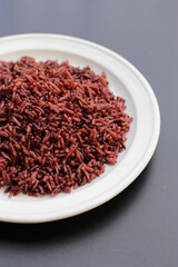 Cooked black berry rice on dark background.