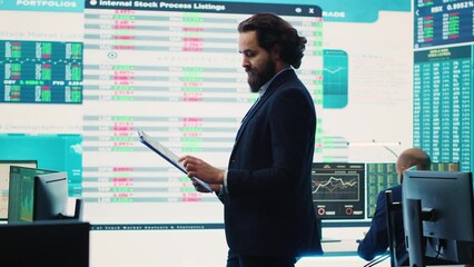 Chief executive officer reviews data shown on big display in the office, screens with infographics, finance analysis and organizational progress. Telecommunications system control room. Camera A.