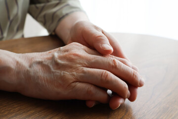 机の上に置いた高齢女性の手元のアップ
