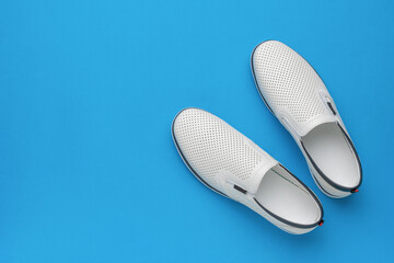 Minimalist White Slip-On Shoes on Blue Background - Stylish Footwear Concept