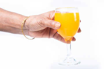 Hand holding a glass of orange or mango juice isolated on a white background.