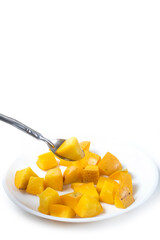 Sliced mango fruit on a white plate with spoon isolated on white background. Vertical short