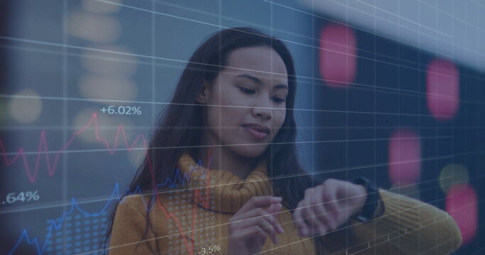 Image of multiple graphs with changing numbers over smiling asian woman scrolling on smartwatch