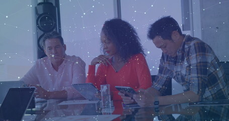 Image of screens with numbers and graphs over diverse colleagues discussing in office