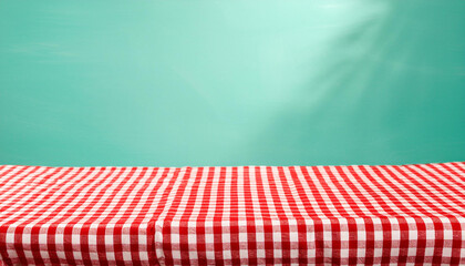 Empty wooden deck table and red checked tablecloth over mint wallpaper background