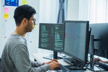 Asian man  prompt engineer develop coding app with software data sitting in front of computer...