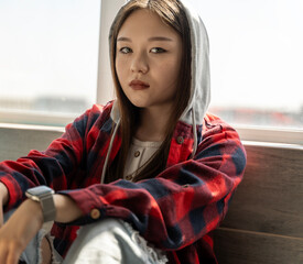 Porter Beautiful serious Asian teenager girl sitting by the window and looking at the camera