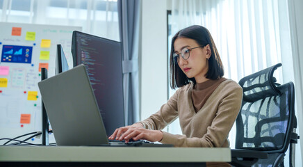 Asian prompt engineer develop coding app with software data sitting in front of computer monitor at...