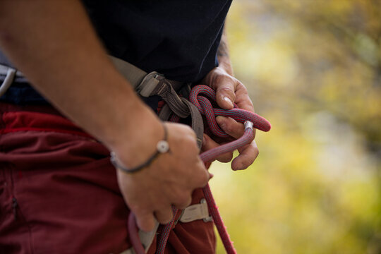 Man tying climbing knot with autumn tree background