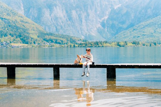 Teen boy on lake with corgi dog, best friends