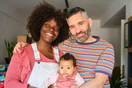 Portrait of a multiracial family with a baby at home.