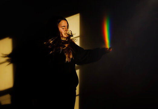 Beautiful teen holding rainbow in sun and shadows