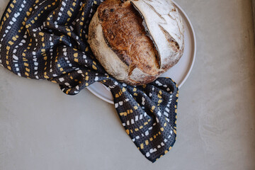 Rustic loaf of bread on a plate with a patterned cloth