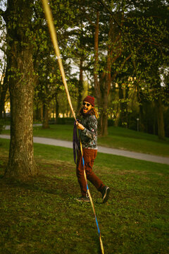 Man sets a slackline in the city park.