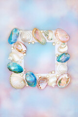 Shell and pearl abstract background frame on rainbow sky  with a variety of mother of pearl shells. Natural summer nature design, beach and seaside art.