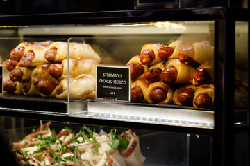 Iberian sausage rolls in a display case, close up.