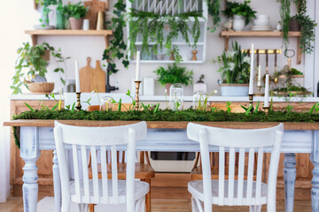 Cozy Wooden cuisine cabinet furniture, utensil, decorations and houseplants on shelves. Dining room with table and chairs. Stylish Interior home kitchen in scandinavian style with green plants in pots