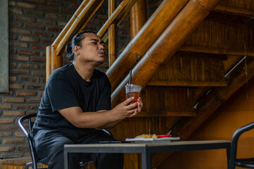 Young Asian man, digital nomad working remotely from cafe, using laptop and smartphone. young Asian men are hanging out in a cafe with an industrial theme