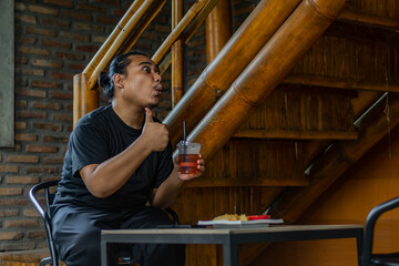 Young Asian man, digital nomad working remotely from cafe, using laptop and smartphone. young Asian men are hanging out in a cafe with an industrial theme
